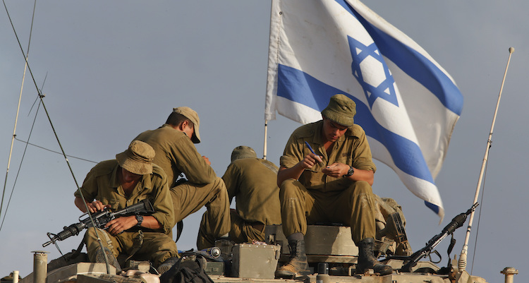 Israeli soldiers, backdropped by the national flag